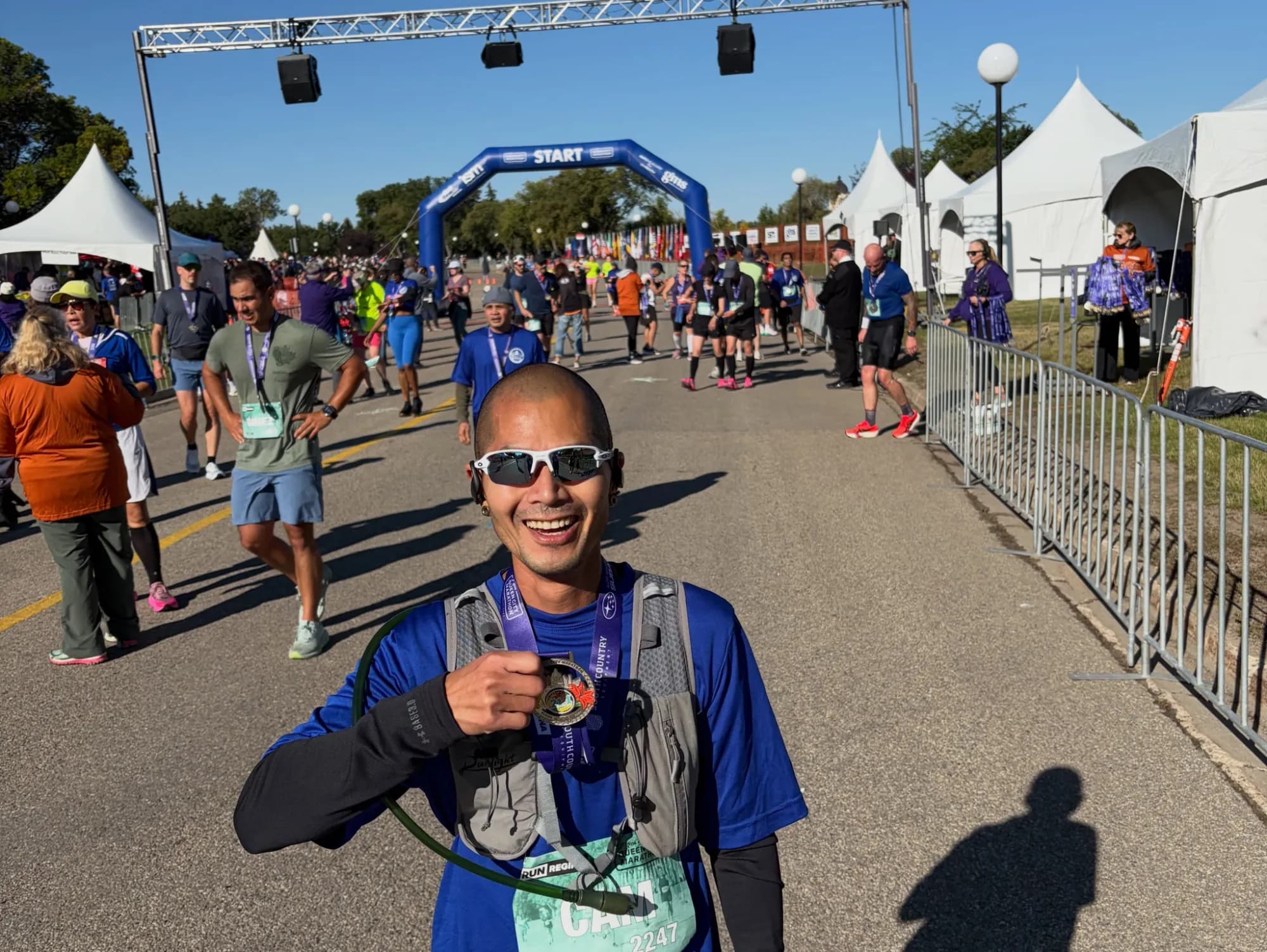 Cam Tran smiling with his finisher's medal at a marathon start line