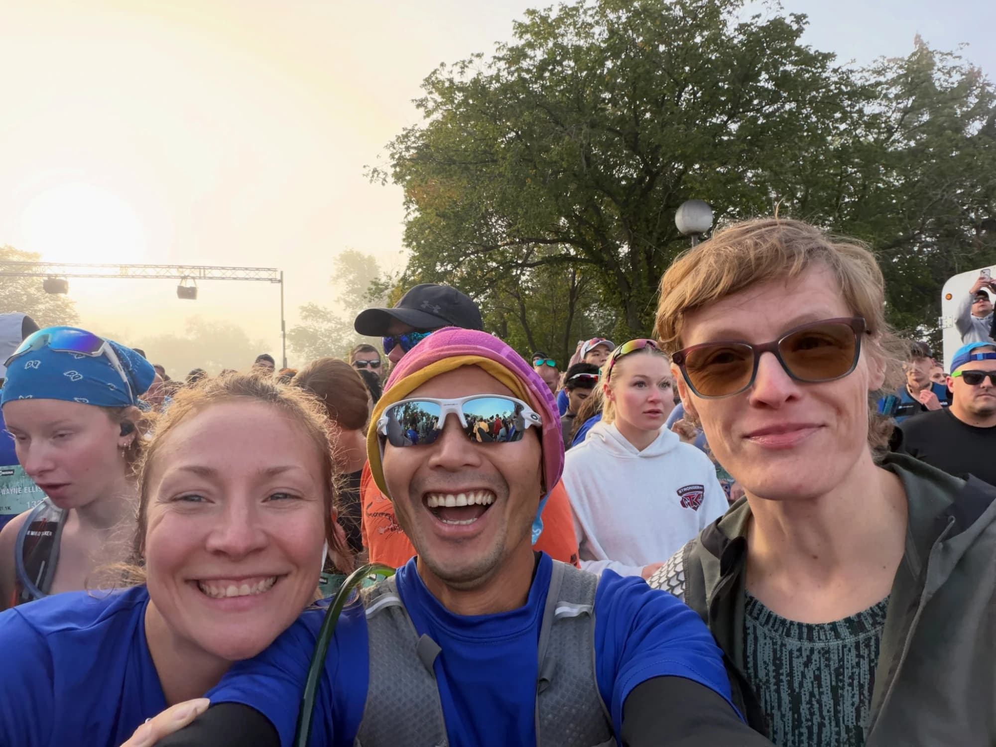 Cam grinning in a selfie with friends at a foggy sunrise start line